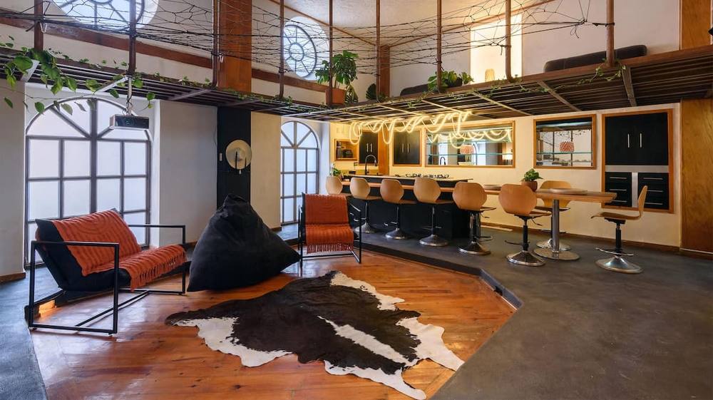 Sala de doble altura con barra y ventanales de arco · set principal
