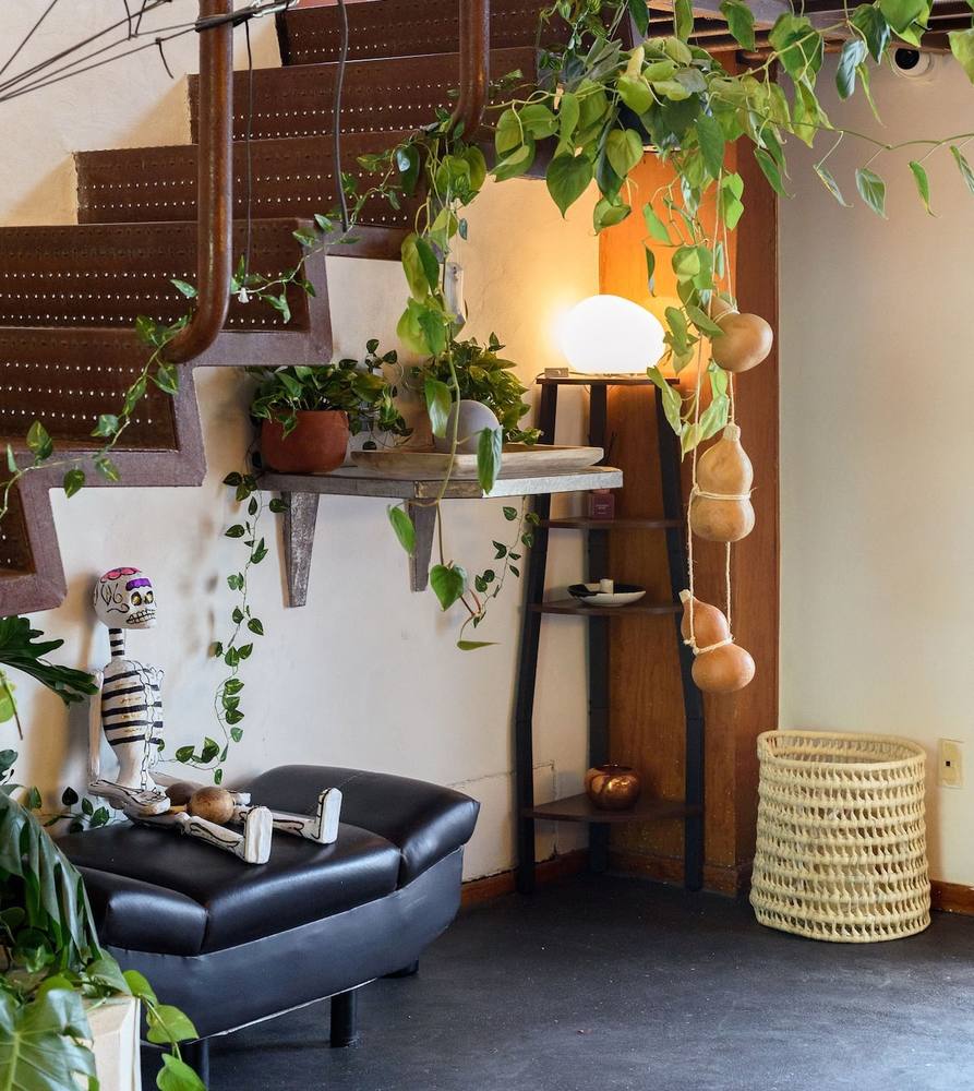 Muro de plantas, sofá de piel y repisa de madera